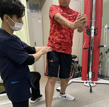 ケーブルカラム(赤色マシーン)でのエクササイズ (左:理学療法士 右:学生)